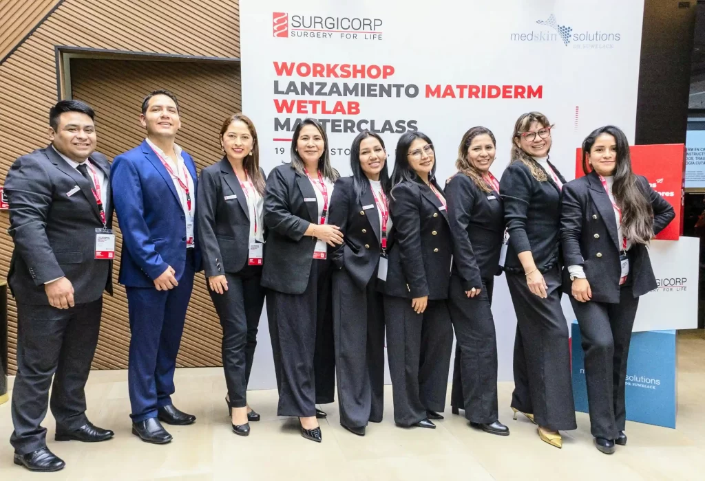 Equipo de Surgicorp en el lanzamiento de MatriDerm en Perú, posando frente al panel del workshop y wetlab de cirugía reconstructiva.